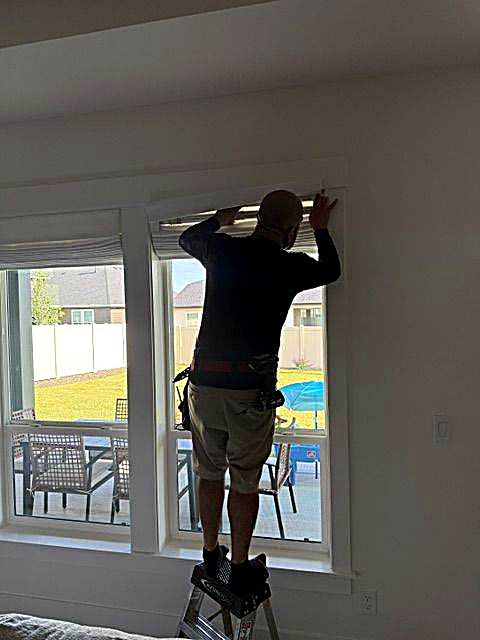 Technician mounting a shade bracket above a window