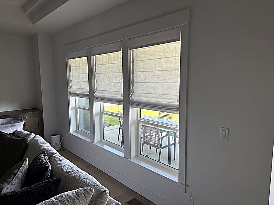 Close-up of woven roman shades over three windows