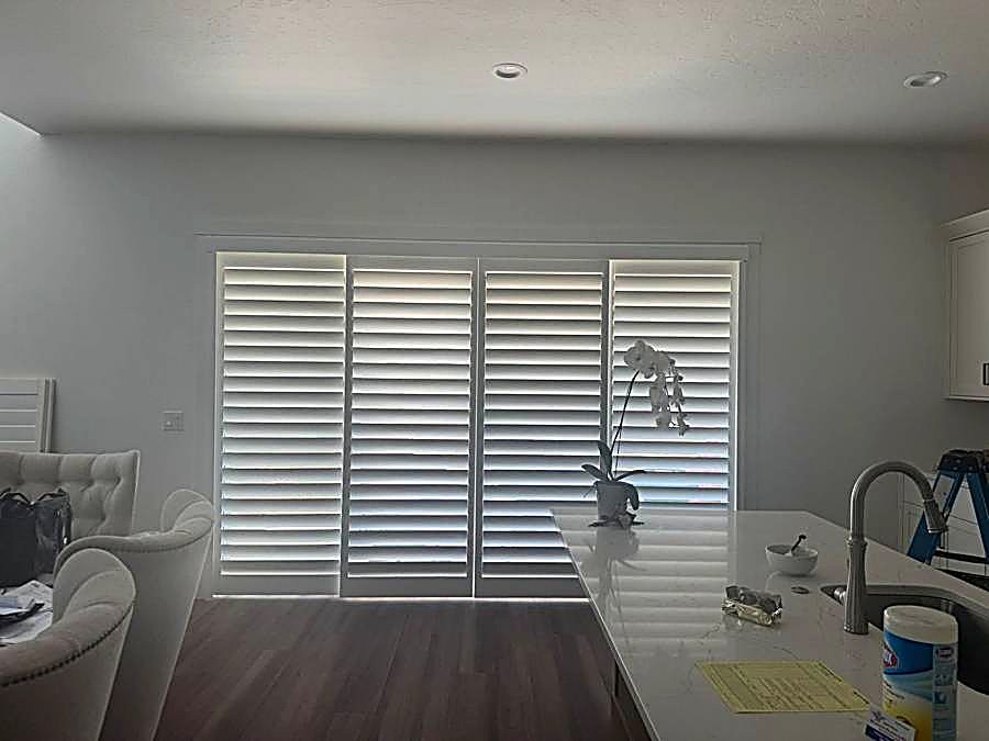 Four-panel plantation shutters over a sliding glass door
